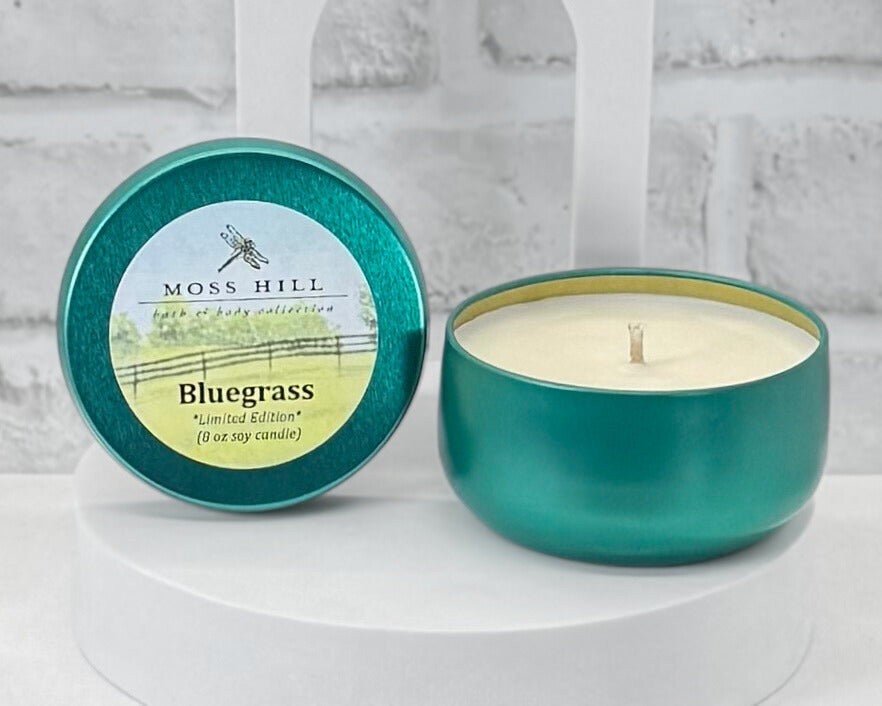 8 oz soy candle in the scent Bluegrass. Hand-poured into a teal container with a Moss Hill logo sticker on the lid.
