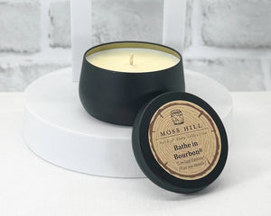 A collection of 8 oz soy candles in various colored tins, with labels indicating different fragrances. Hand-poured in Louisville, KY.