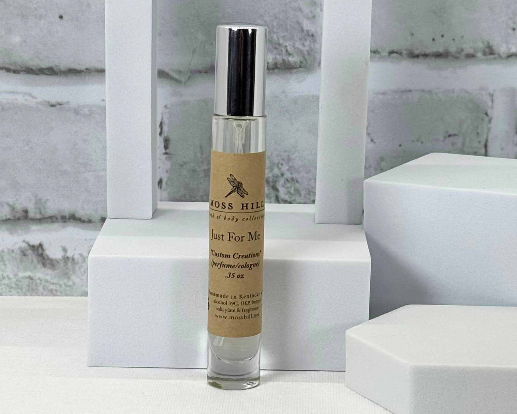 Custom perfume in a clear bottle with a label on a white surface. Made by Moss HIll Bath & Cody Collection