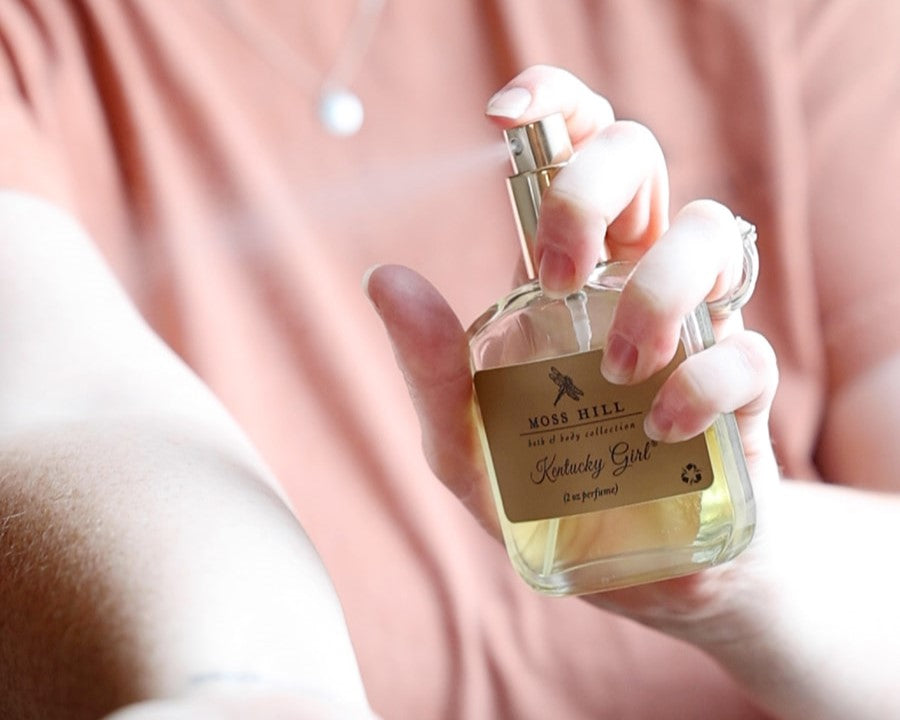 Moss Hill 2 oz spray perfume being misted onto a woman's arm