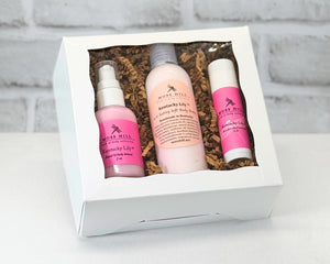 Moisturizing body care gift box set in the fragrance Kentucky Lilly. Three pieces set in a white box with filler paper on a white table.