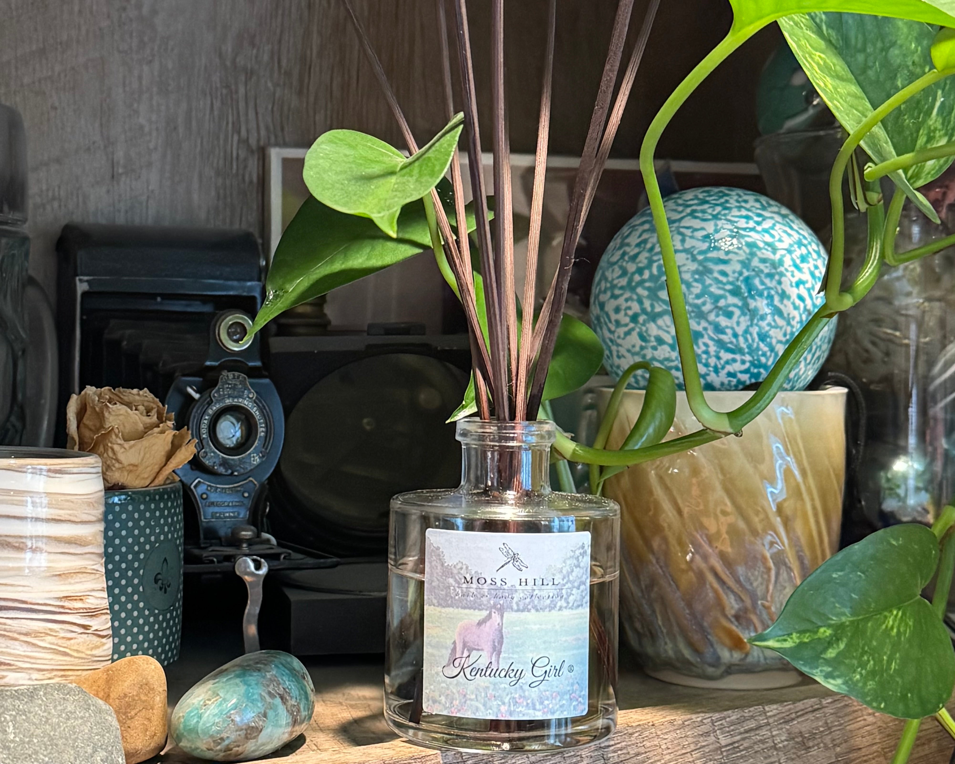 A glass diffuser bottle labeled 'Linden Hill' with decorative elements on a wooden surface.