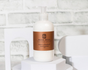 Moss Hill bottle of hanemade body lotion in the secent Bathe in Bourbon on a white surface with a marble background