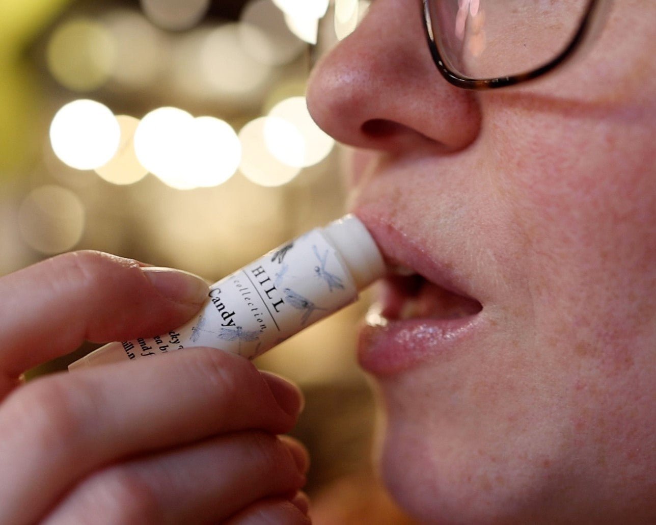 Woman holding lip balm and applying it to their lips.