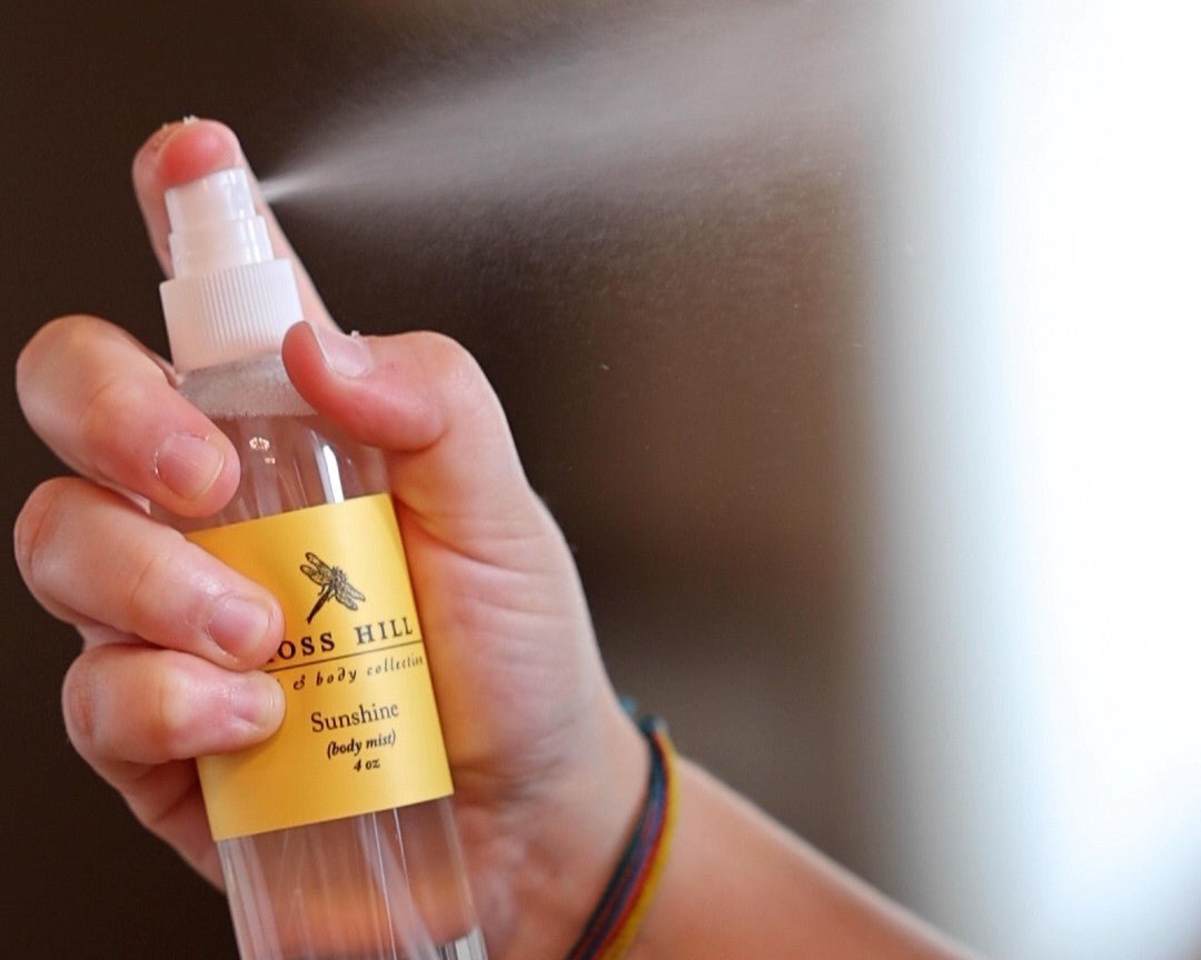 A hand misting body spray into the air.