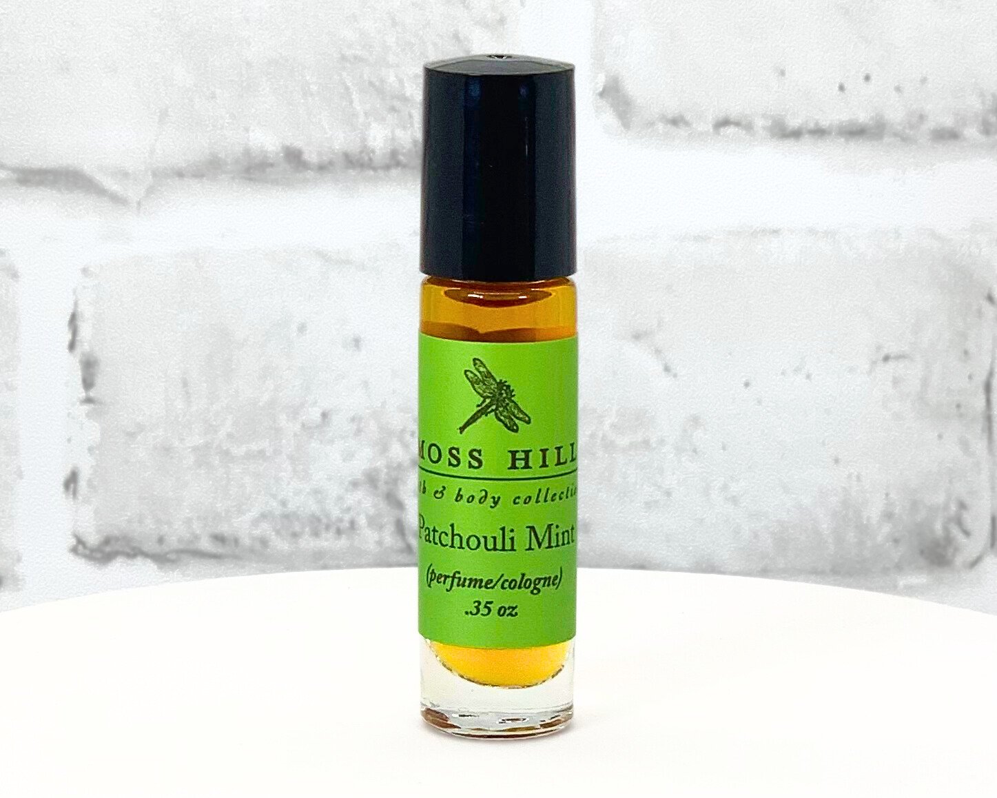 Patchouli Mint scented travel-sized roll-on perfume bottle with green label displayed on a white stand.