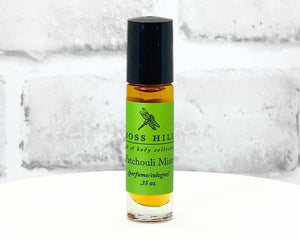 Patchouli Mint scented travel-sized roll-on perfume bottle with green label displayed on a white stand.