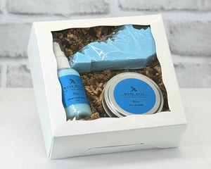 A gift set containing a candle, lotion, and a Kentucky shaped soap packaged in a white box with a clear viewing window. In the scent Blue.
