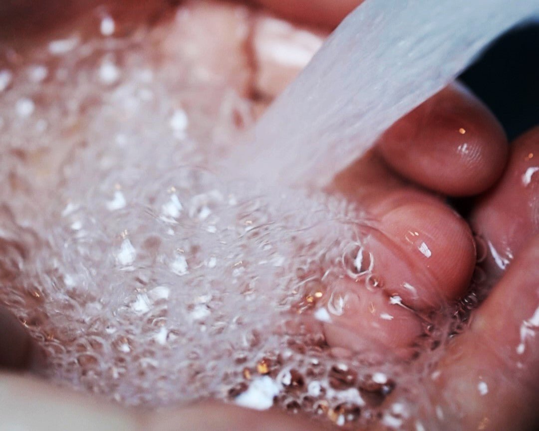 Wet hands with soap bubbles while using Moss Hill Hand Soap.