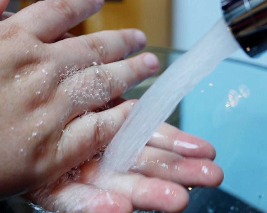 Two hands with soap bubbles on them from washing their hands with Moss Hill hand soap.