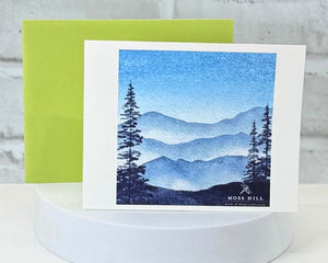 Greeting card with mountain landscape design on a white surface. That represents our Blue scent collection.