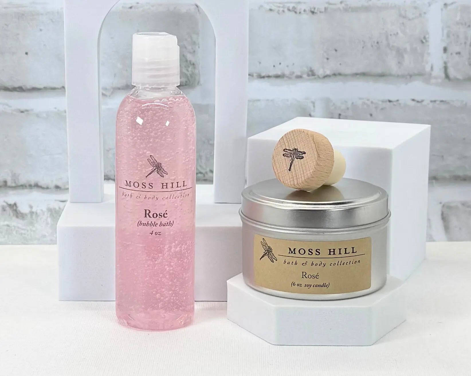 Moss Hill bath and handmade body products including handmade bubble bath and soy candle in a silver tin on a white background.