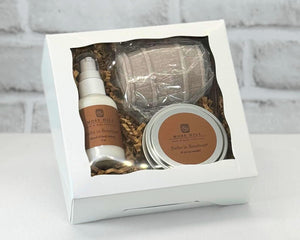 A gift set containing a candle, lotion, and a bourbon barrel shaped soap packaged in a white box with a clear viewing window.