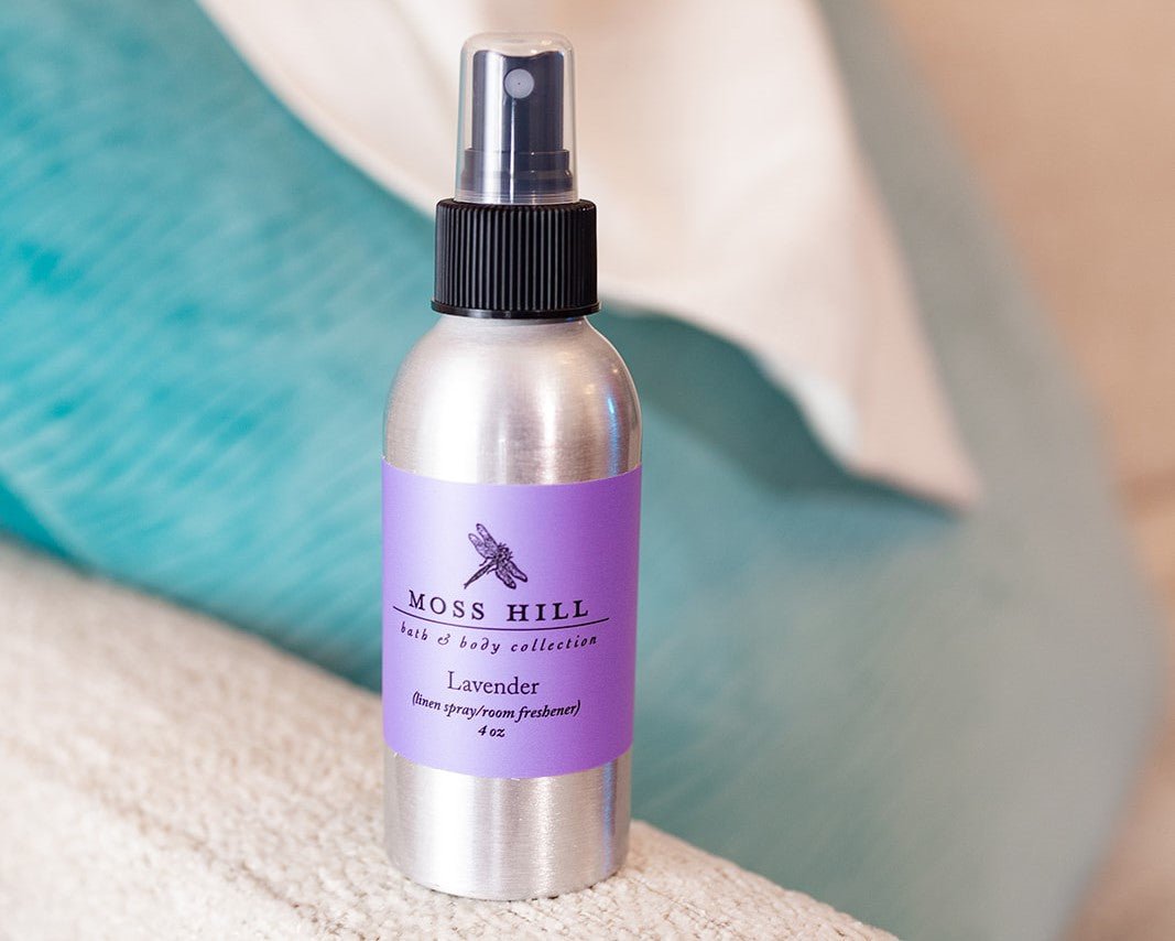 A silver bottle with a black sprayer wrapped in a purple label that says "lavender', 'linen spray', 'room spray'. Handmade in Louisville, Kentucky.