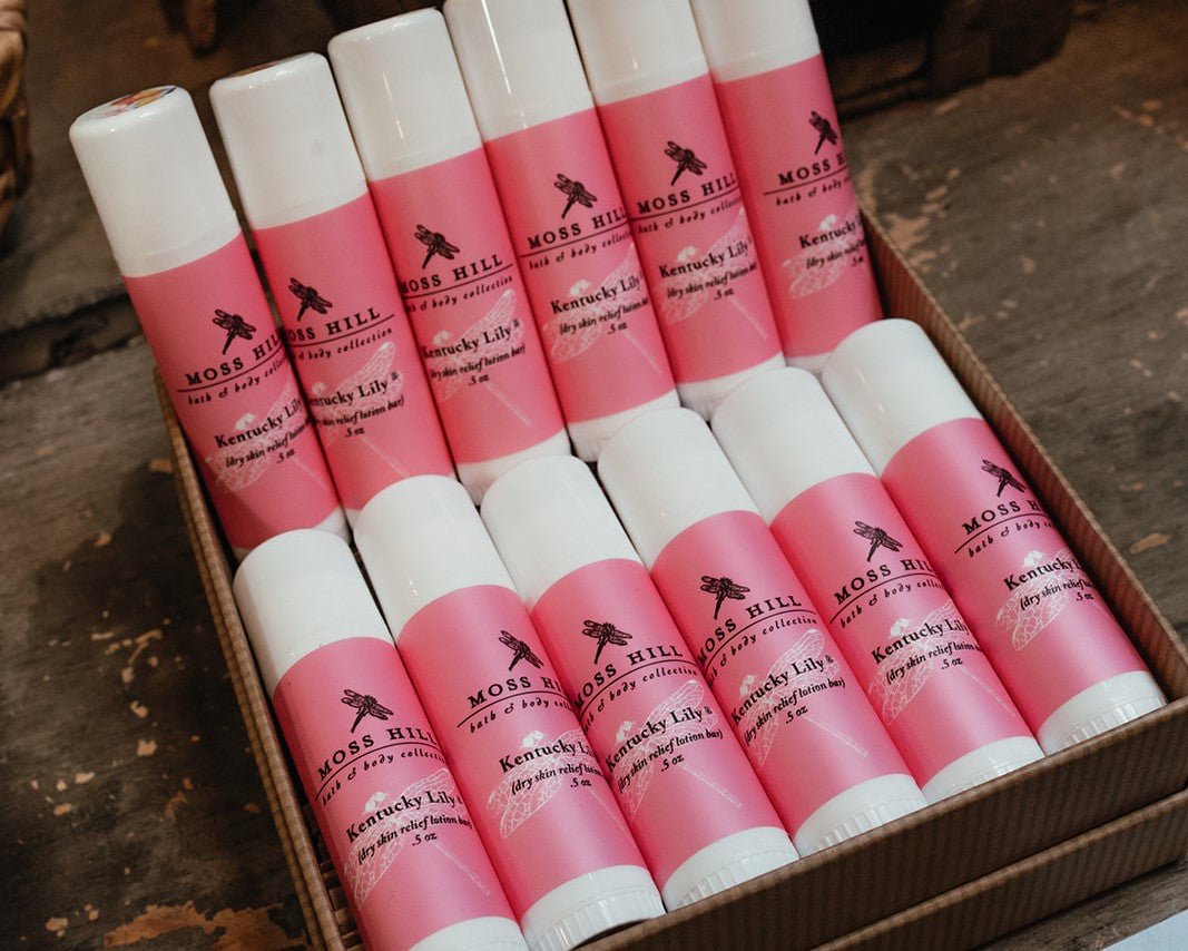 Several tubes wrapped with a pink labels laying in a box to showcase the dry skin relief lotion bar in a retail store