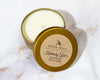 A collection of 8 oz soy candles in various colored tins, with labels indicating different fragrances.