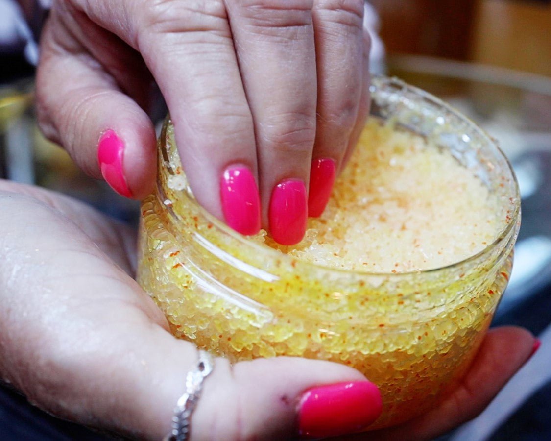 a hand scooping out the yellow body scrub body care product handcrafted by Moss Hill