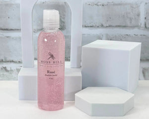Pink bottle of Moss Hill Rosé handmade bubble bath on a white brick background