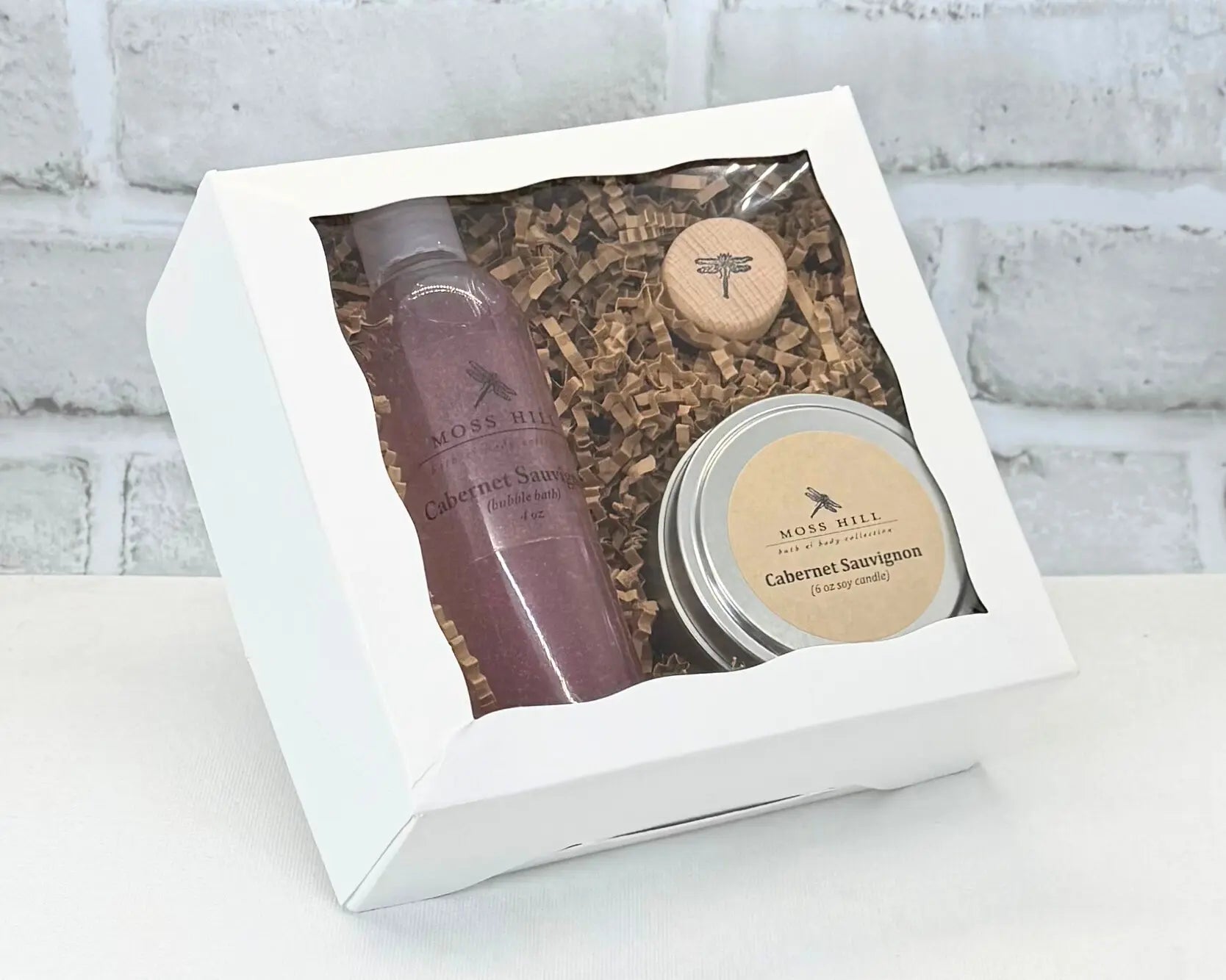 Body care gift set with handmade bubble bath and a soy candle in the scent Cabernet in a white box on a light background