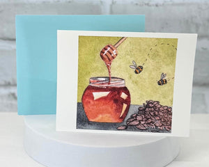 Card with a honey jar illustration and bees, on a white stand with a light blue border. Representing the Honey Almond scent collection at Moss Hill bath and body.