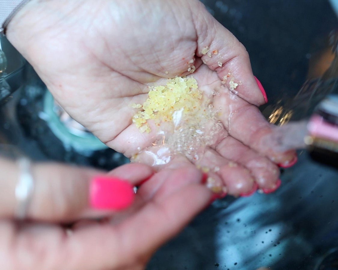 Two hands in water using the handmade sea salt body scrub.