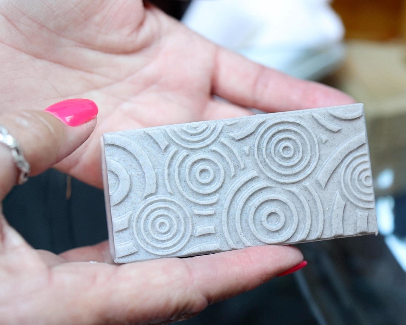 A woman holding exfoliating bar soap with embossed details in two hands.