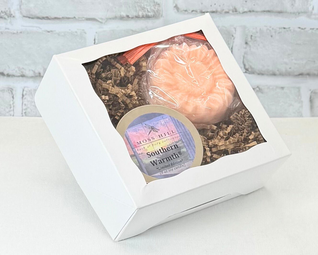 2 piece body care gift set with handmade soap and soy candle. In a white box with a brick wall background