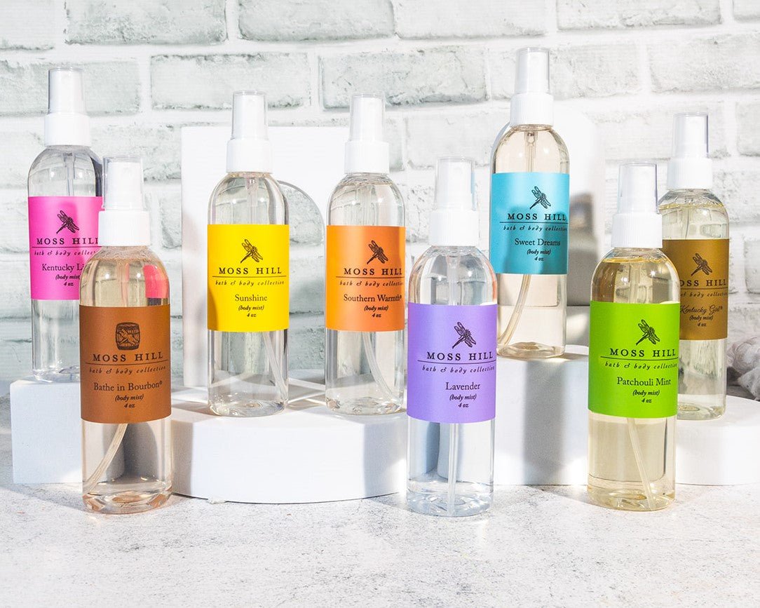 A collection of clear glass bottles with various colored labels, representing different fragrances of body mist.