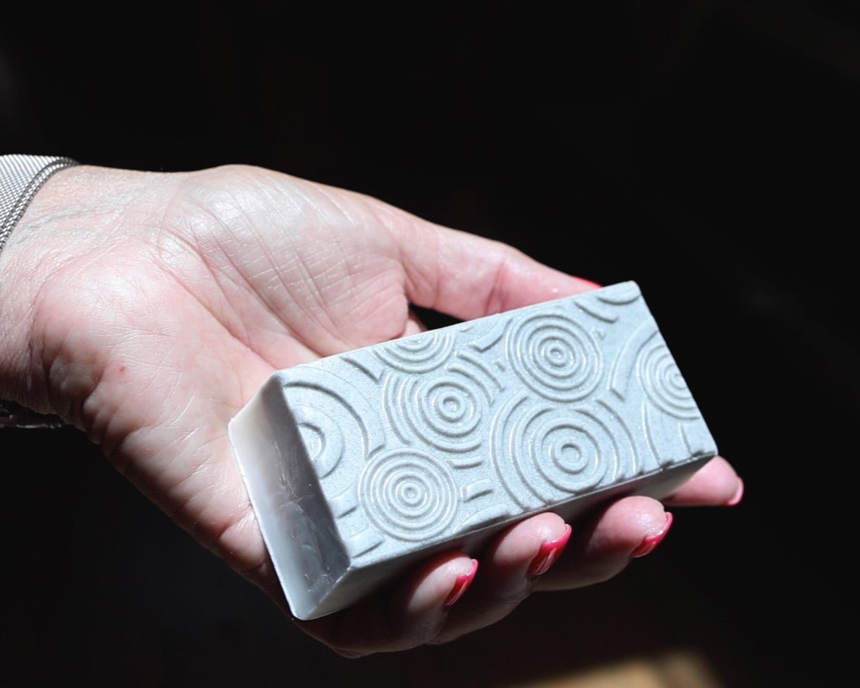 A bar of exfoliating soap scrub being held in one hand.