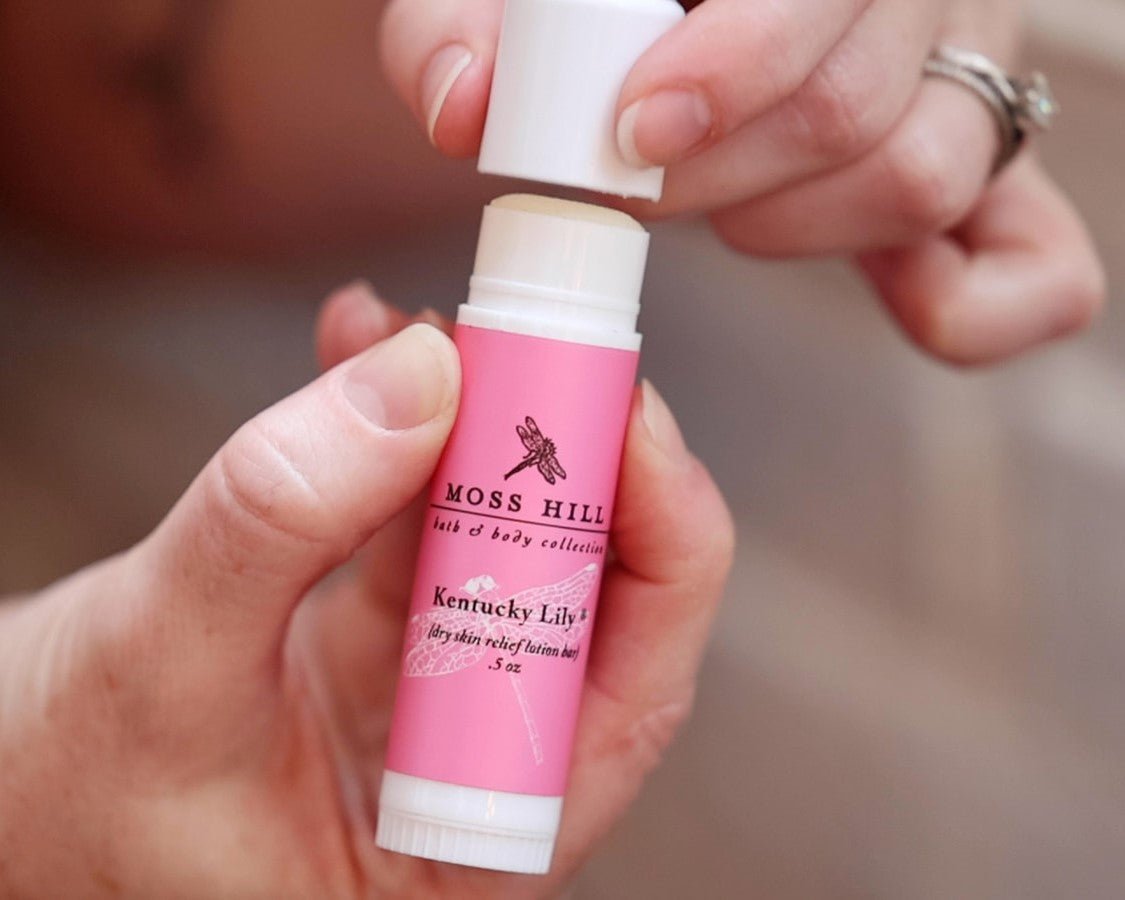 A tube of the dry skin relief lotion bar with a removed white cap being held in one hand